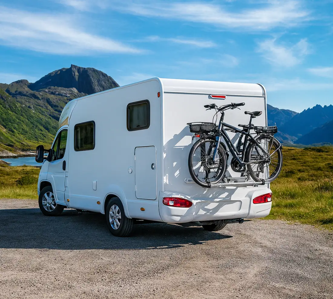 Wohnmobil mit zwei Fahrrädern auf dem Heckträger in den Bergen