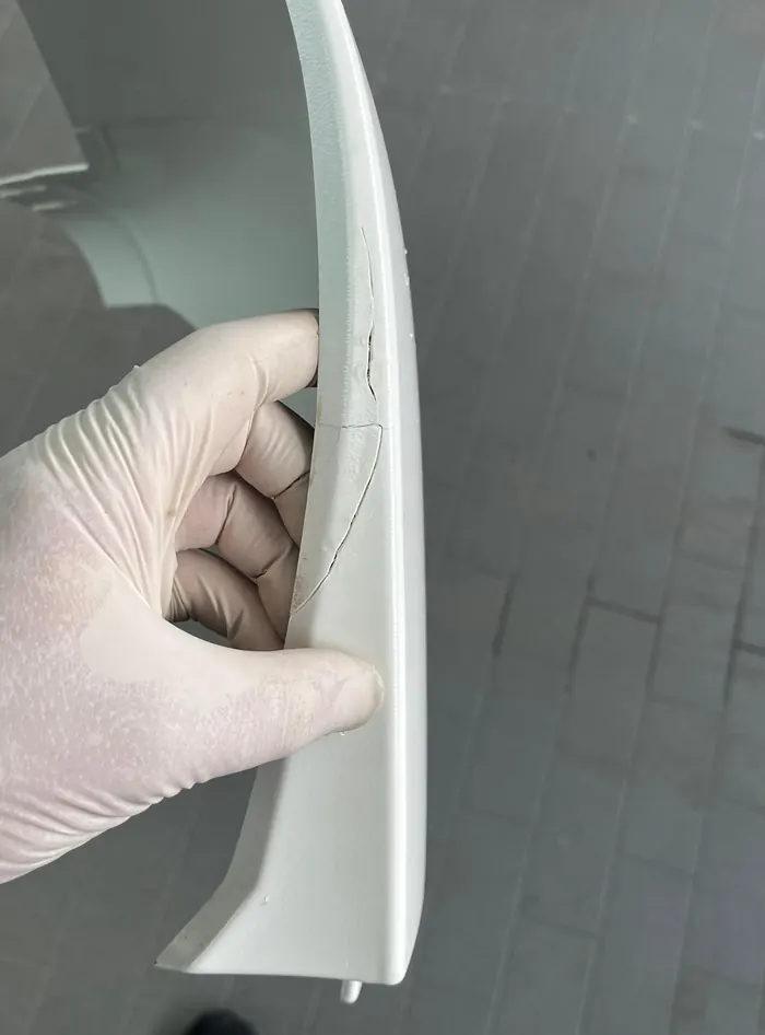 Repariertes Kunststoffteil in der Hand eines Mechanikers mit Arbeitshandschuh