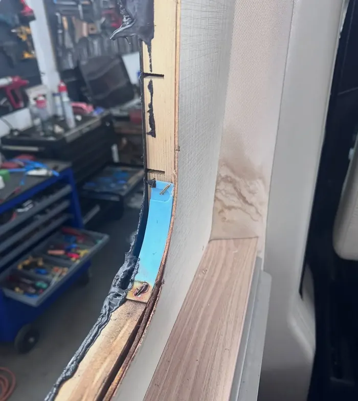 Geöffneter Türrahmen eines Wohnwagens während der Reparatur, im Hintergrund die Werkstatt